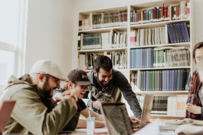 trois collègues de start-up rigolant en regardant un écran d'ordinateur