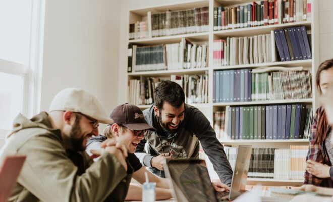 trois collègues de start-up rigolant en regardant un écran d'ordinateur